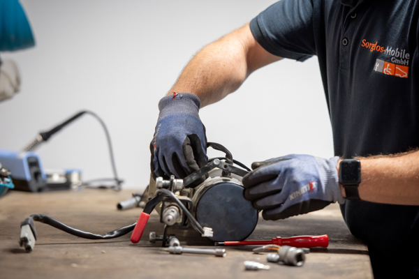 Eine Detailaufnahme eines Mitarbeitzers von Sorglos Mibile in der eigenen Werkstatt beim Reparieren.